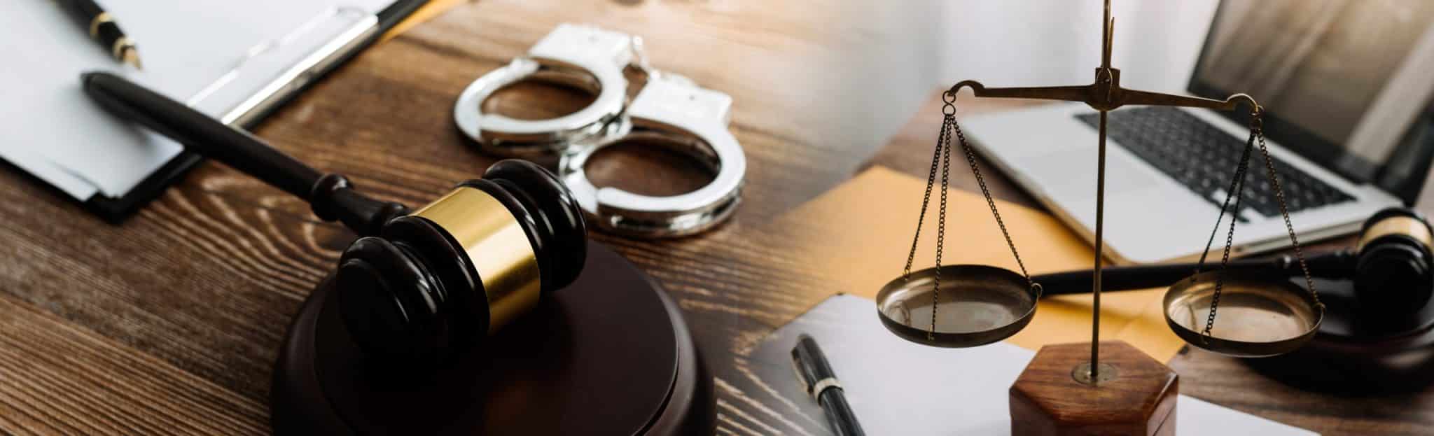 desk with scales of justice judges gavel and handcuffs on it