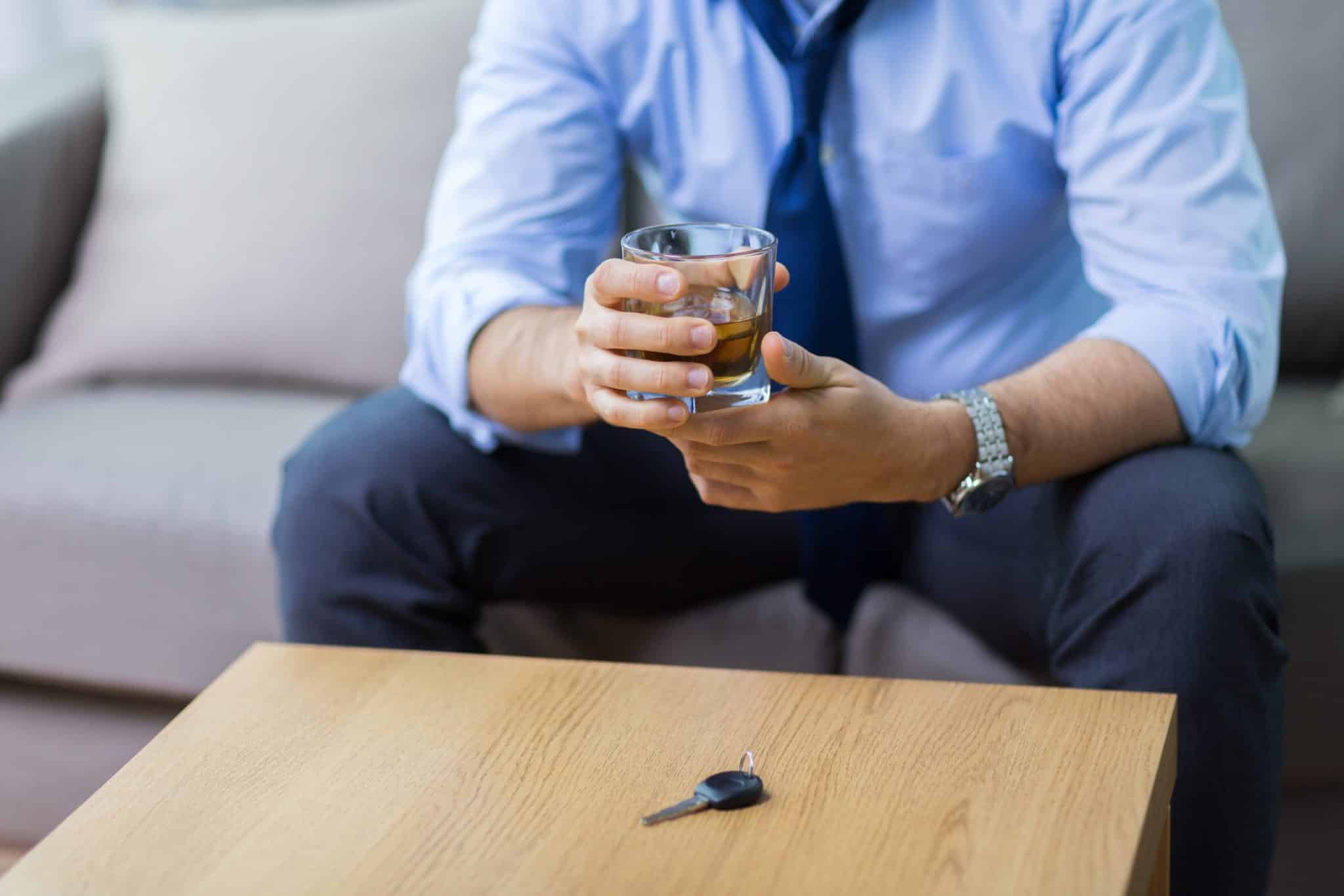 a man sitting at the table holding a cocktail and car key